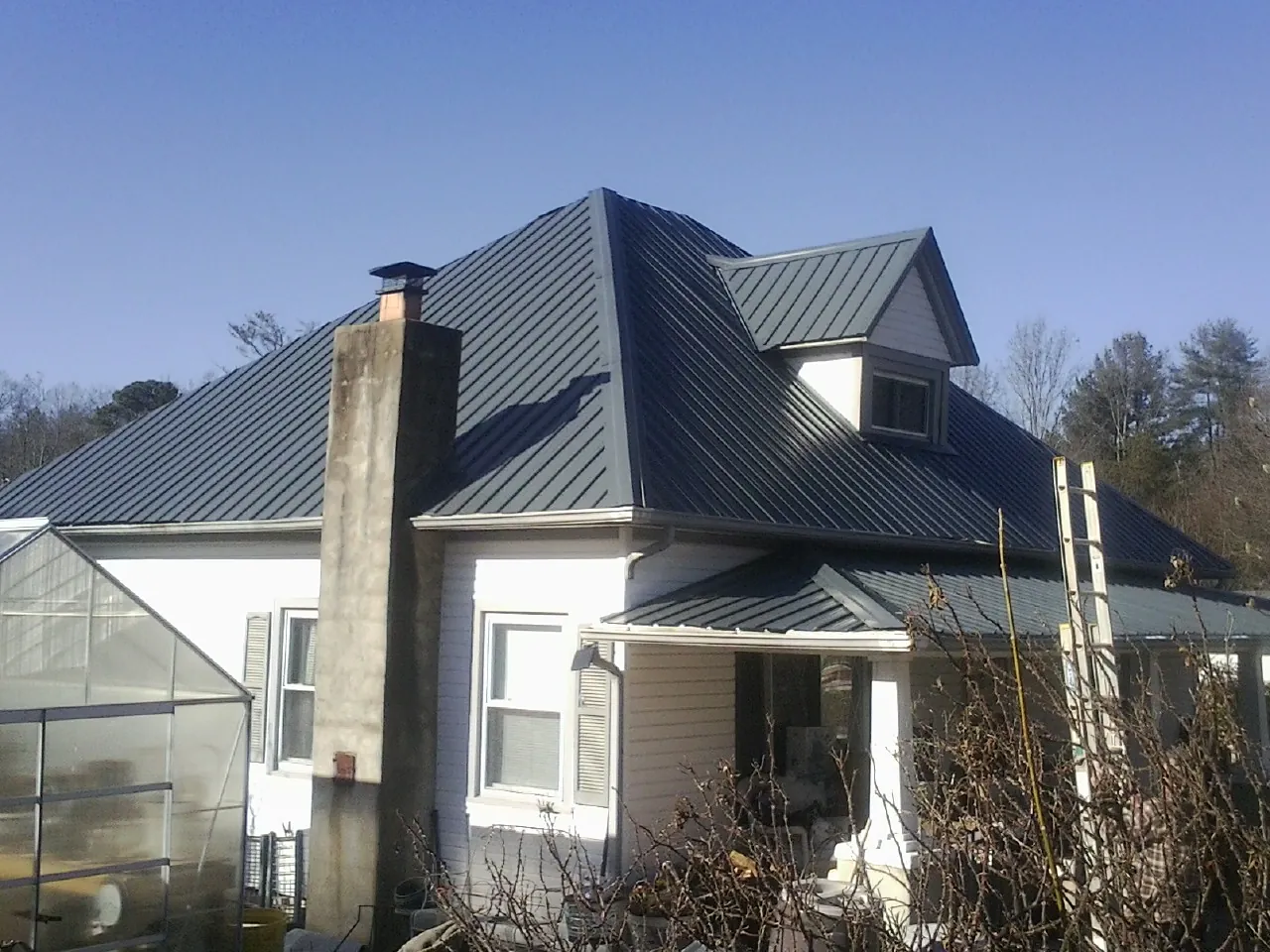 Dark blue standing seam metal roof on a white farmhouse with dormer — Slate & Tile Roof Repair by Roofing Brothers in Hiko