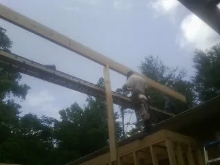Carpenter setting a ridge beam over a new addition frame — Ice Dam Removal by Roofing Brothers in Hiko