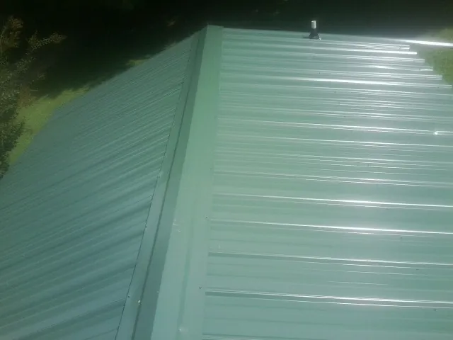 New green metal panels meeting at the ridge of a roof — Flat Roof Repair work by our crew in Hiko