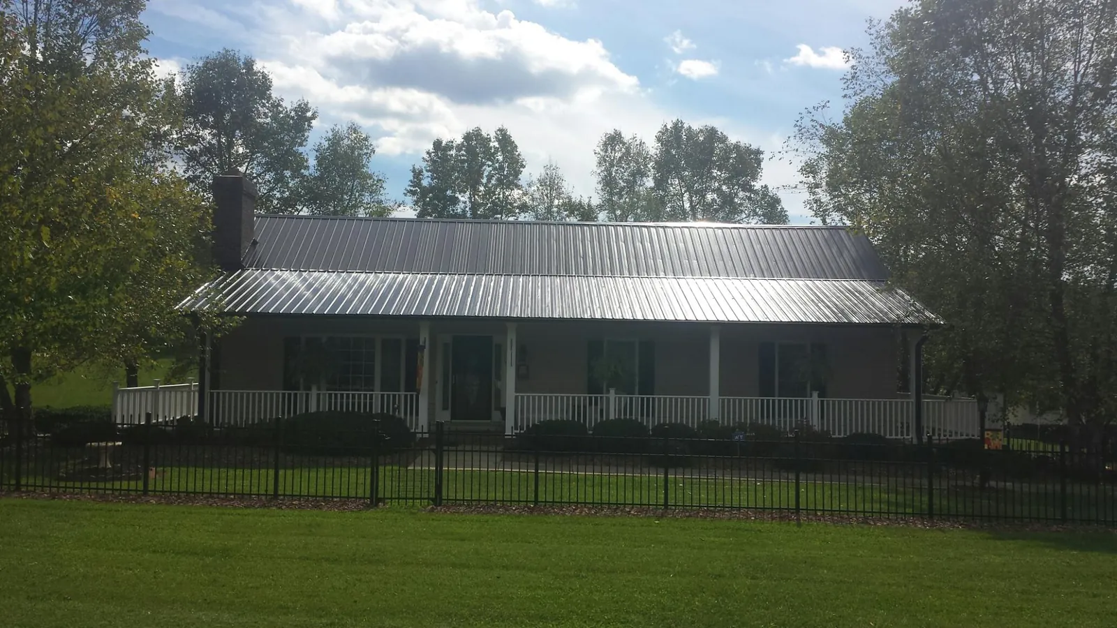 Gray metal roof on a brick ranch with a full width front porch — Gutter Guard Installation work by our crew in Hiko
