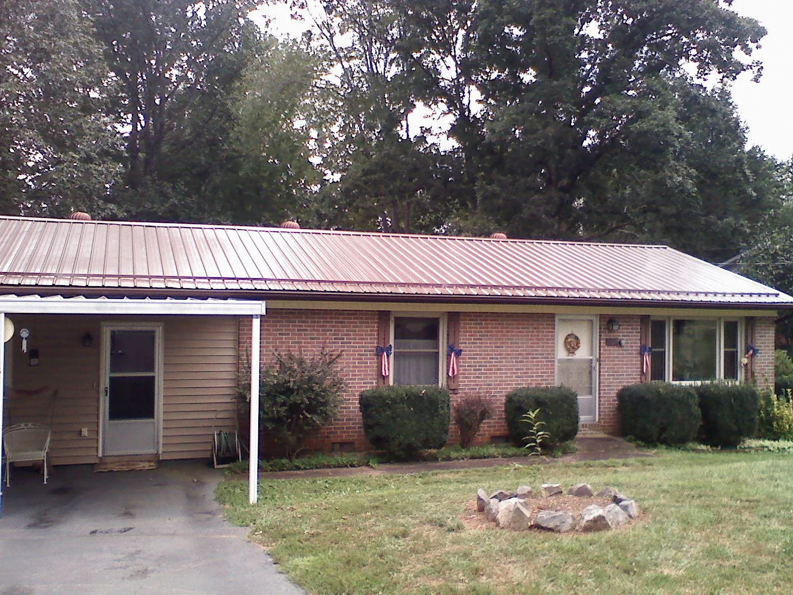 Bronze metal roof and carport on a brick ranch home — Roof Repair work by our crew in Hiko