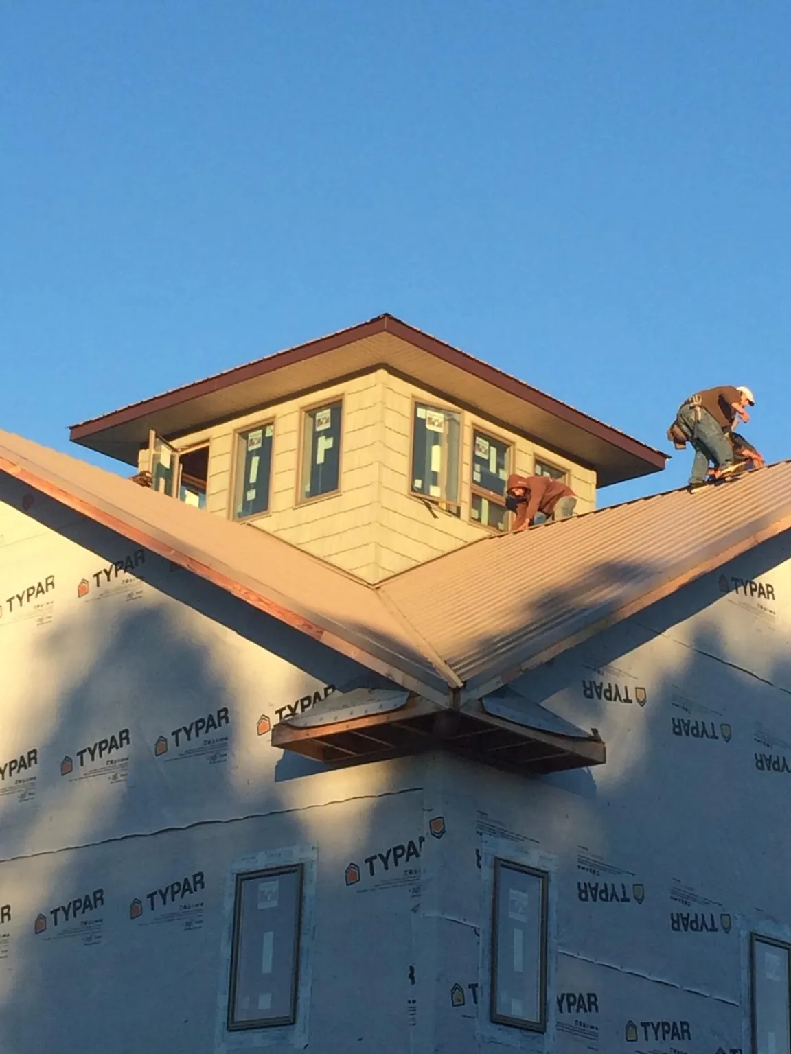 Roofers working around a rooftop cupola on a new metal roof at sunset — Roof Waterproofing in Hiko by Roofing Brothers